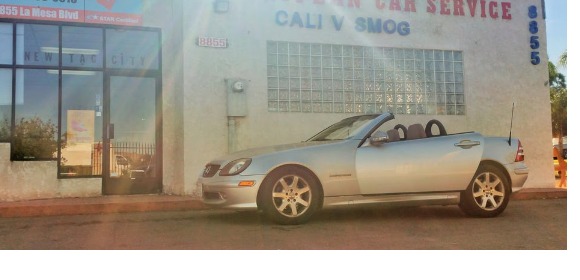 Building front with Cali v. Smog signage and a silver Mercedes SLK out front